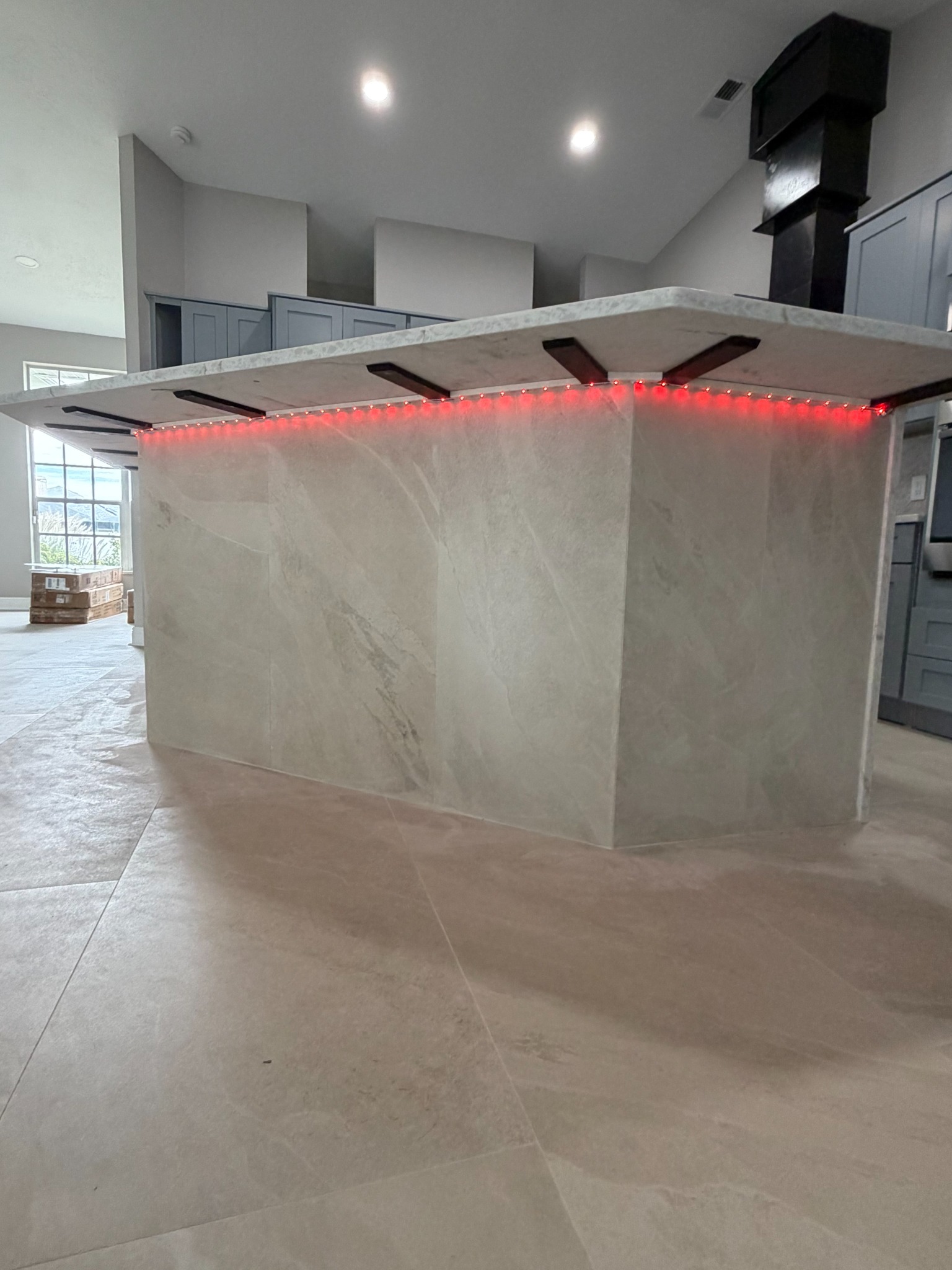 Stone waterfall kitchen island with red color-changing LED strip lighting installed beneath the countertop overhang.