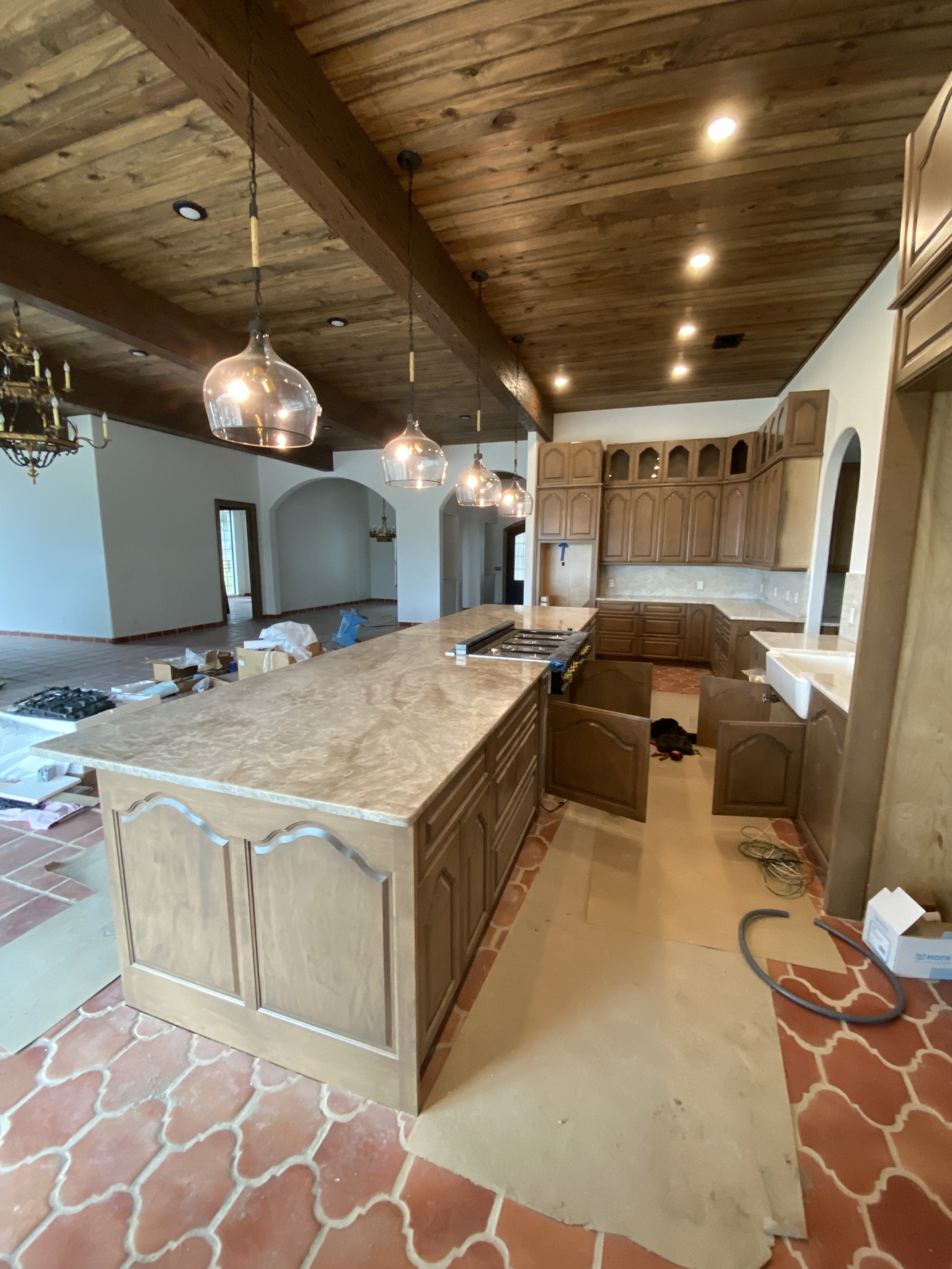 Rustic kitchen with a wood plank ceiling, recessed LED downlights, and glass globe pendant lights hung over a stone island.